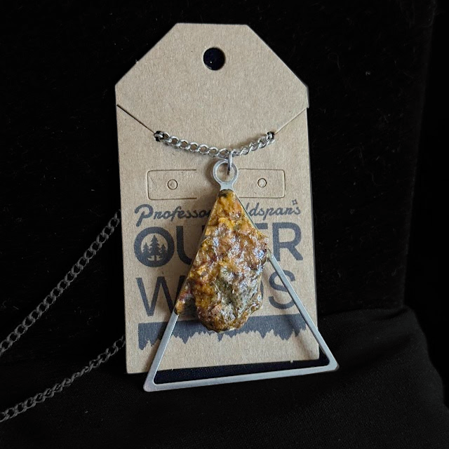 Necklace with a pendant on a branded card against a black background