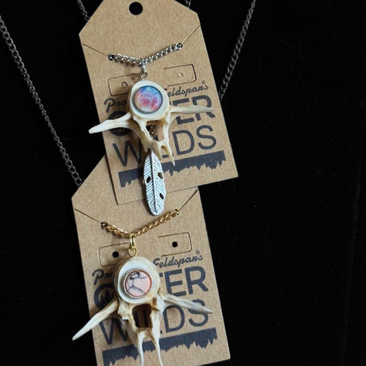 Necklace with bone and feather design on a 'OUTER WILDS' branded card against a black background.