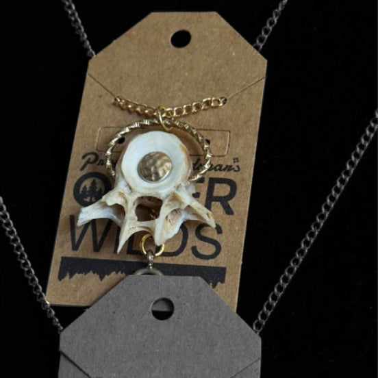 Necklace with a bone fish pendant on a branded tag against a black background