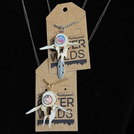Two necklaces with fish bone pendants on a 'OUTER WILDS' branded card against a black background.