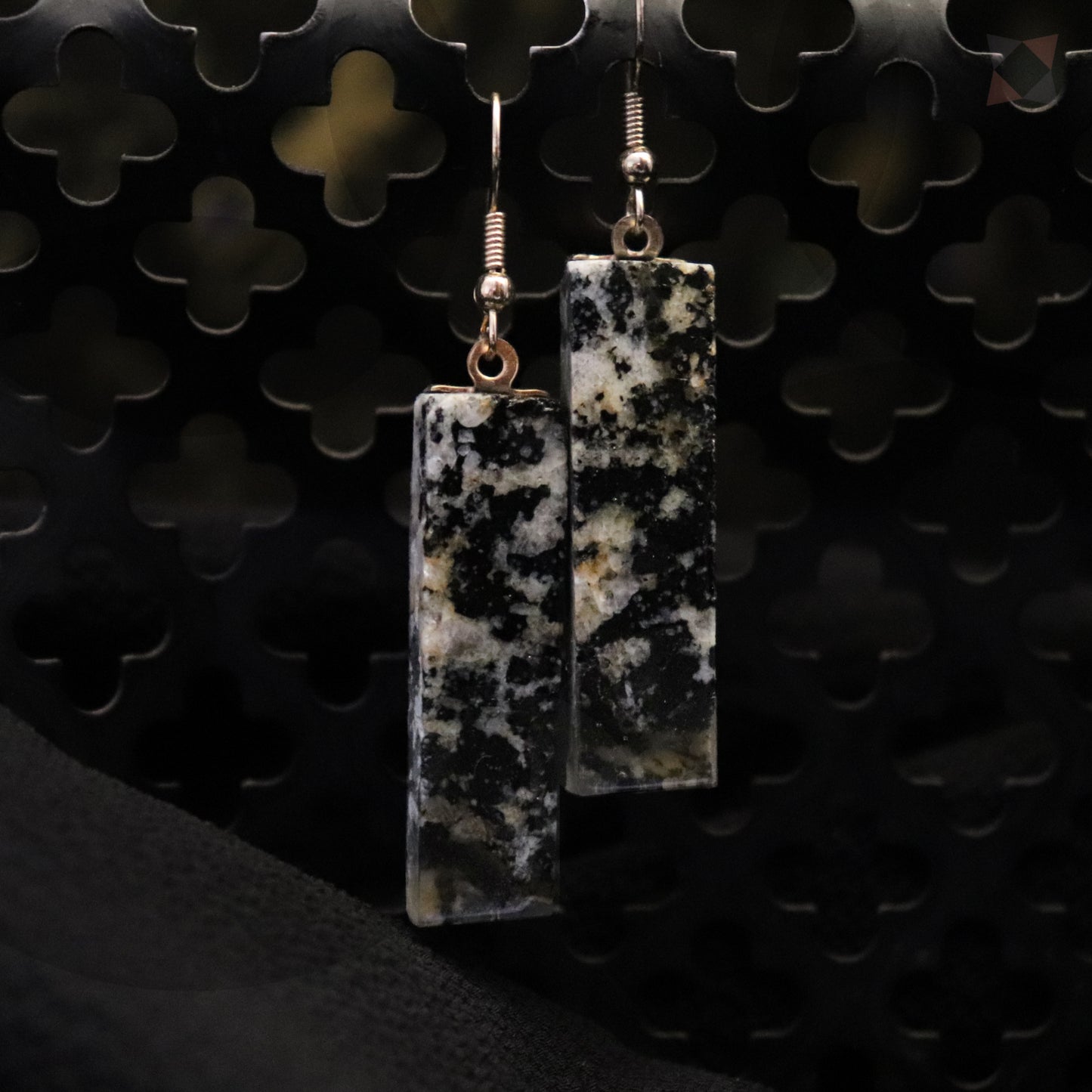 Pair of rectangular earrings with a speckled pattern on a textured black background