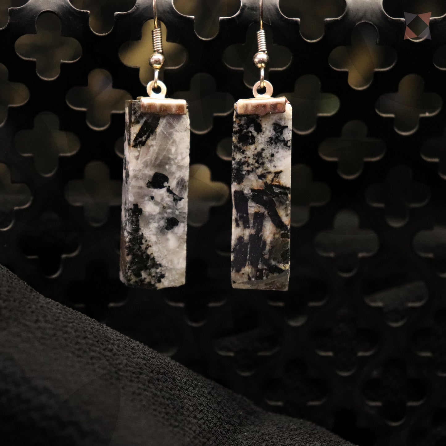 Pair of rectangular stone earrings on a textured black background