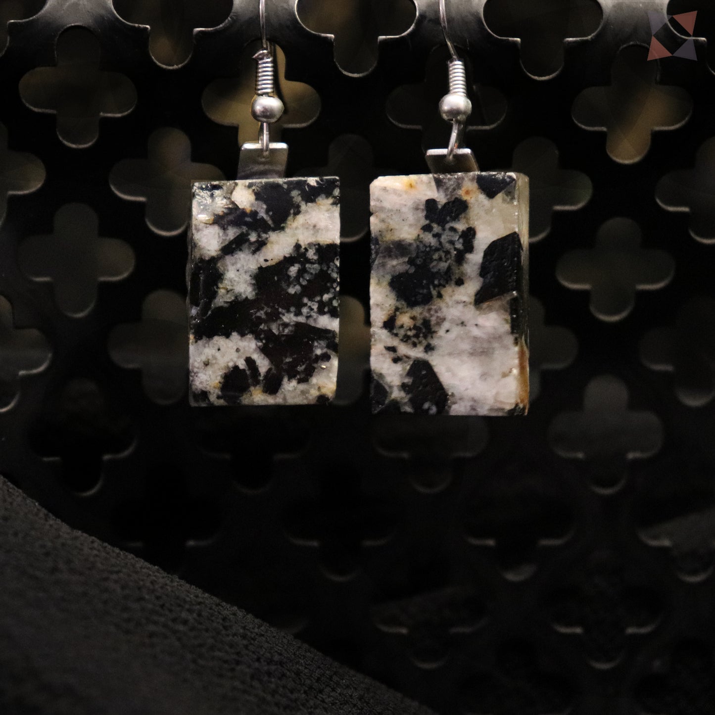 Square stone earrings on a dark textured background