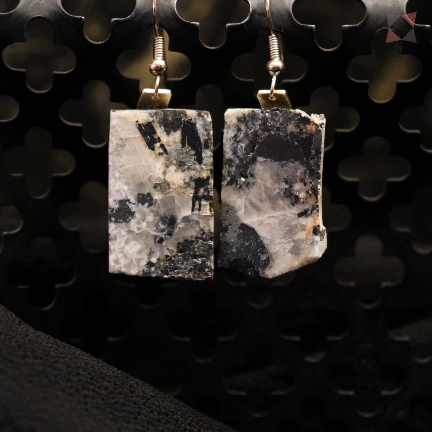 Pair of square stone earrings on a black textured background