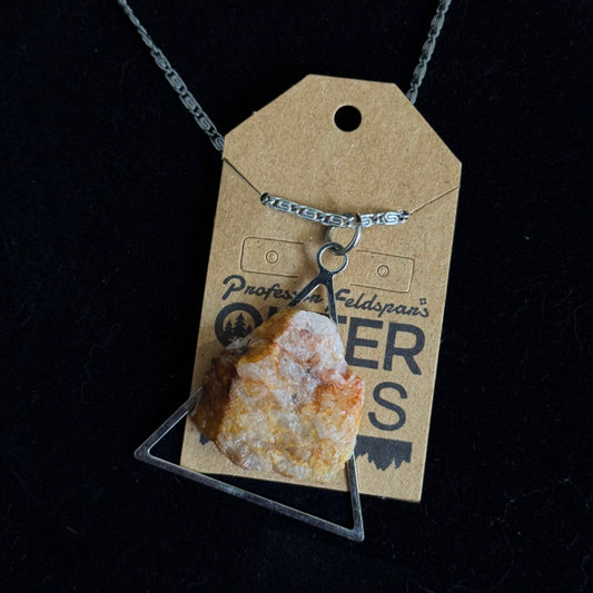 Necklace with a triangular pendant on a branded card against a black background