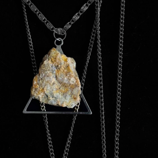 Necklace with a triangular pendant featuring a natural rock or crystal on a black background