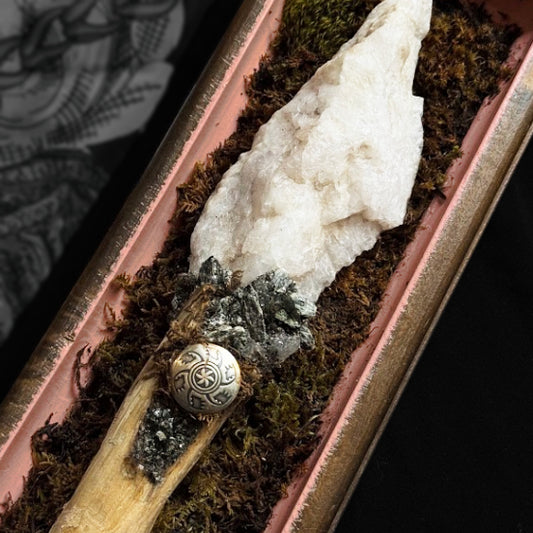 Decorative item with white crystal, moss, and metallic button on a dark background