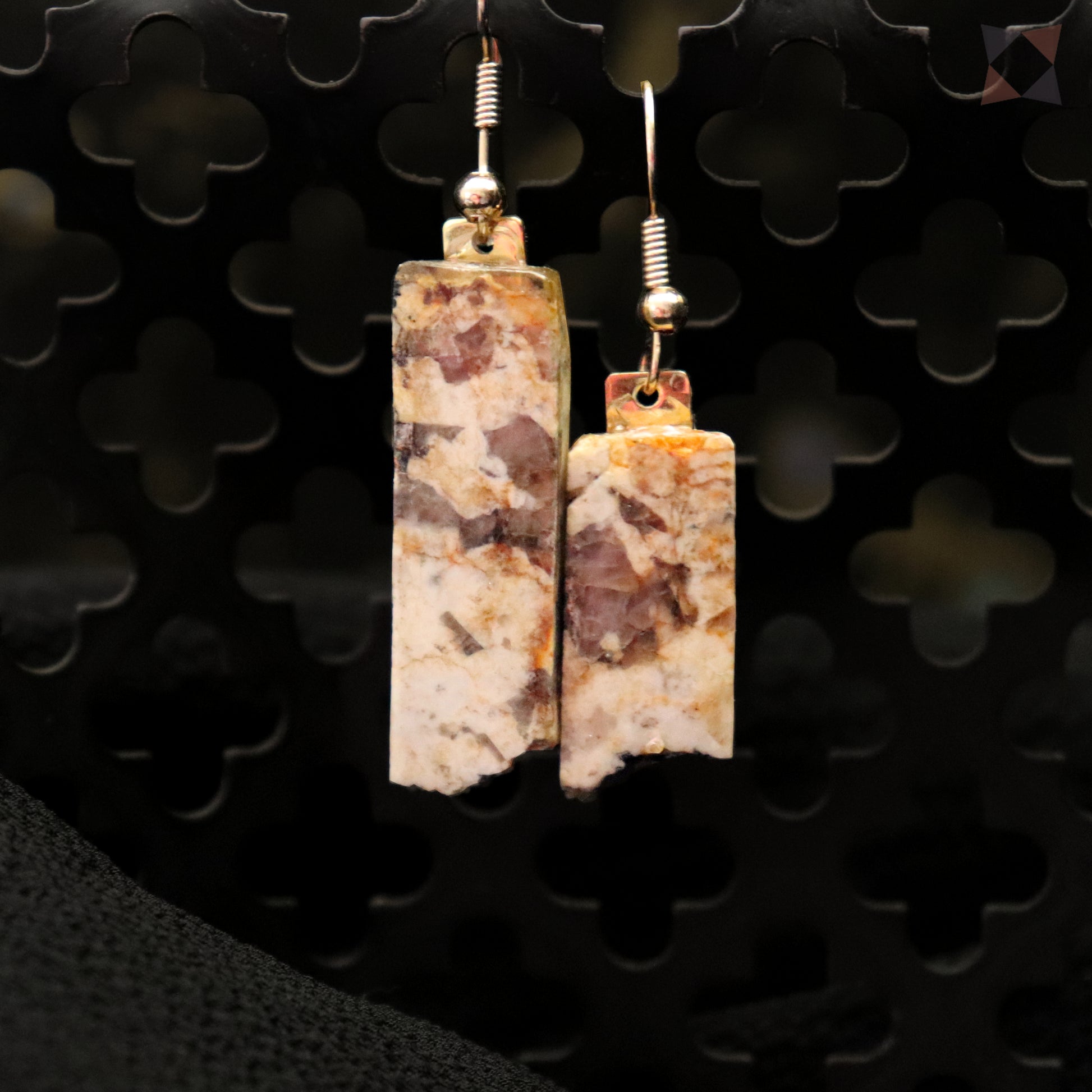 Pair of earrings with rectangular stone-like pendants on a dark background