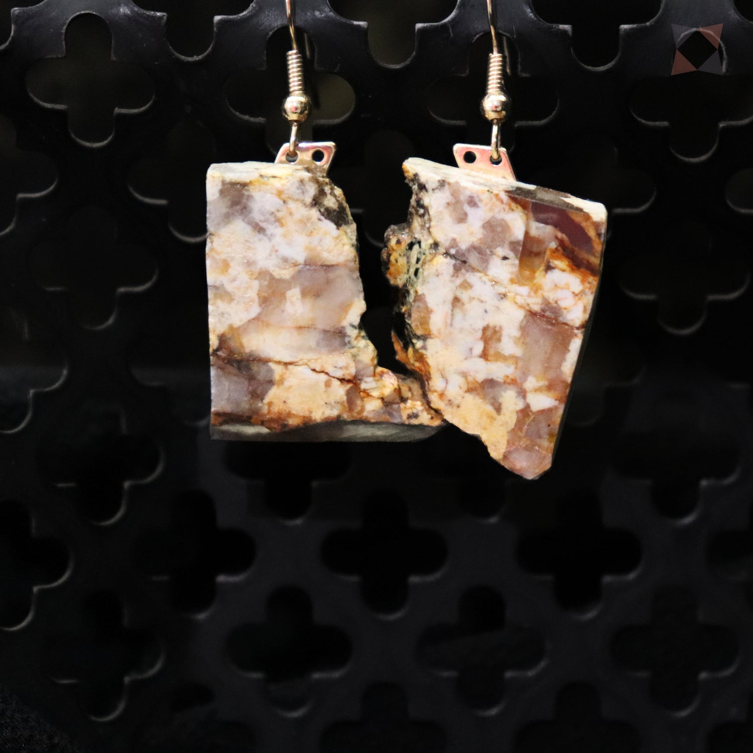 Pair of earrings with natural stone design on a black textured background