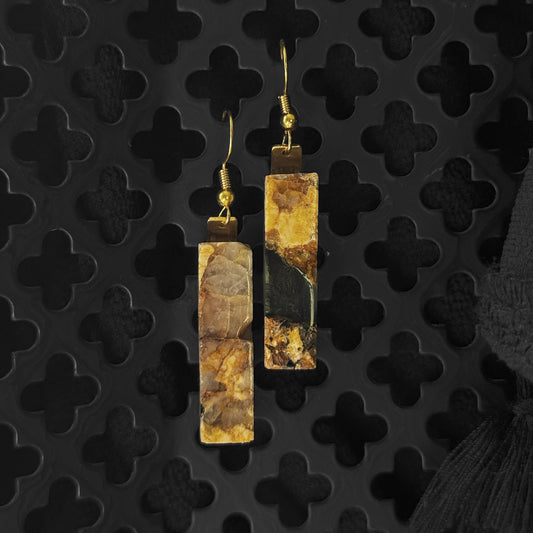 Pair of earrings with a textured design on a black textured background
